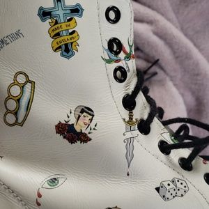 White doc martens with little drawings on them.